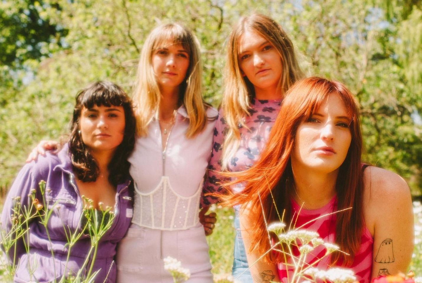 Four woman dressed in pink & purple in a field